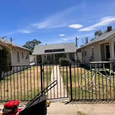 Dry, patchy lawn behind a front gate before service